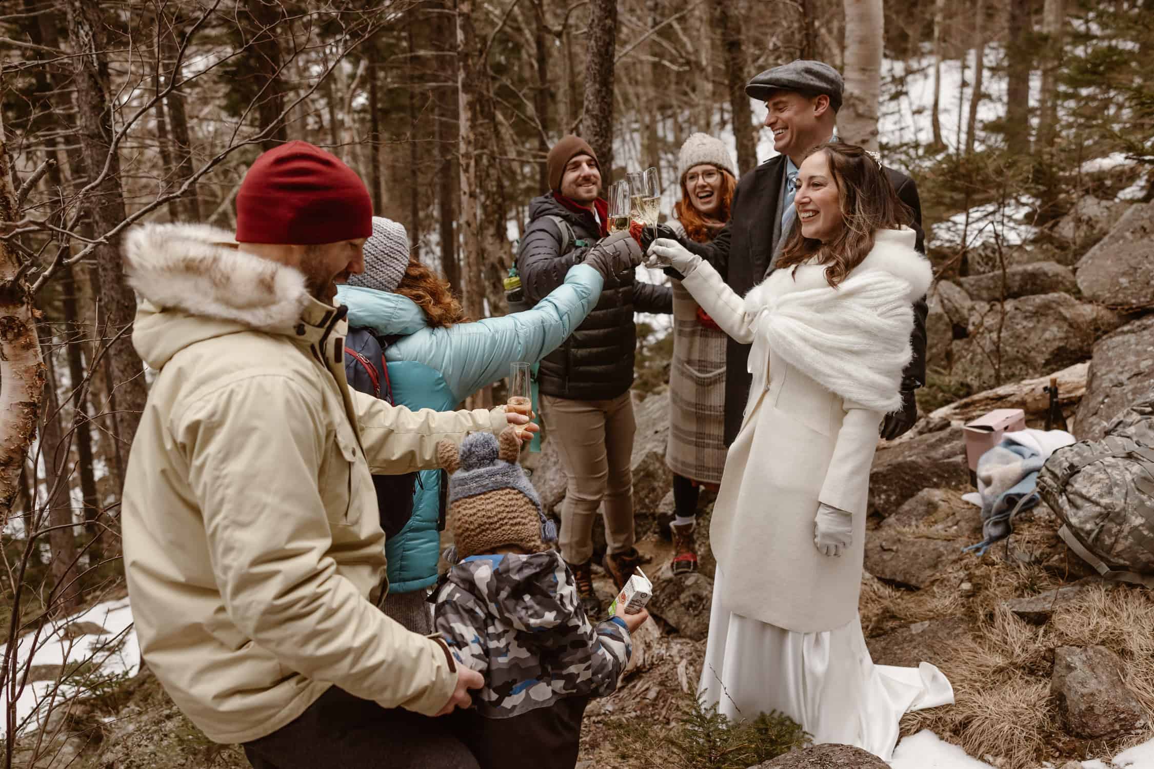 A family clinking champagne glasses for a toast, celebrating the couple's rappel elopement.